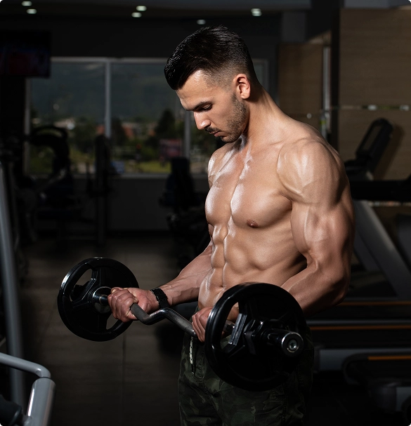 A shirtless man lifts a dumbbell while exercising in a gym, showcasing his strength and focus.
