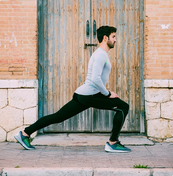 A man performs a squat in front of a wooden door, focusing on his form and balance.