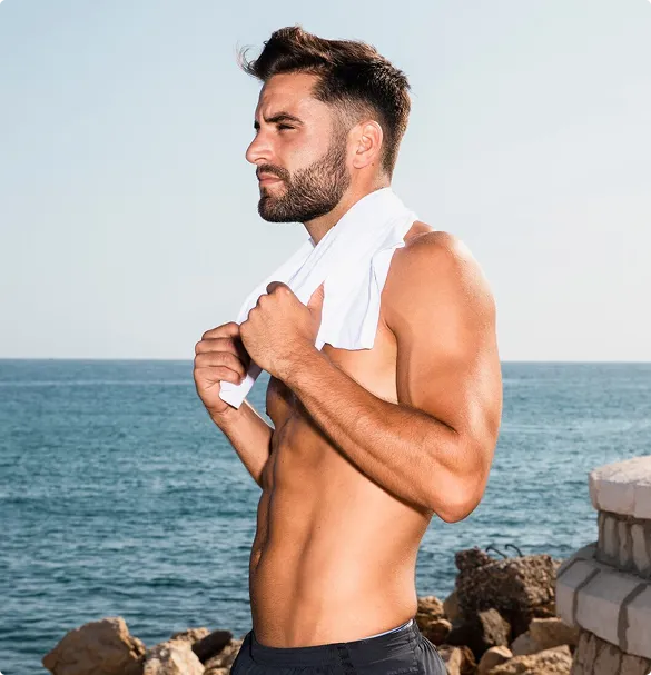 A shirtless man draped in a towel around his neck, exuding a casual and laid-back demeanor.