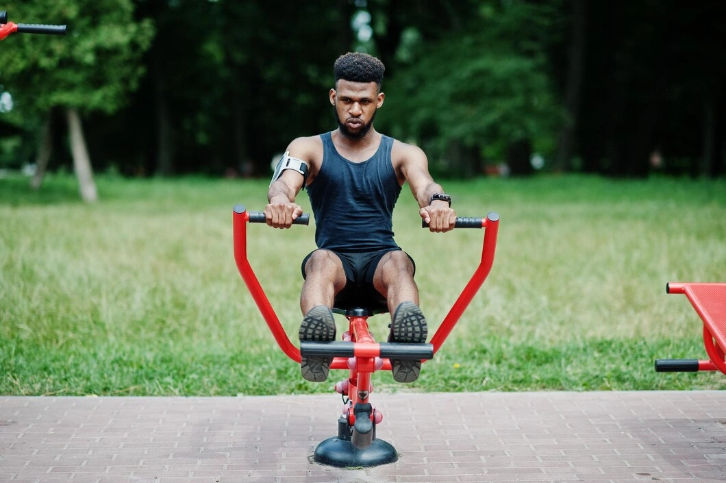 A man sits on a red exercise bike, focused on his workout in a bright, well-lit room.